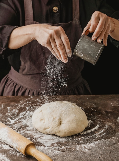 Female chef dusting flour over pizza dough