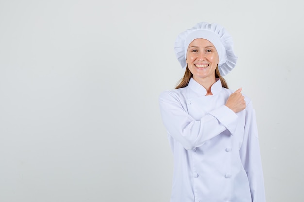 Female chef gesturing with clenched fist in white uniform and looking cheerful