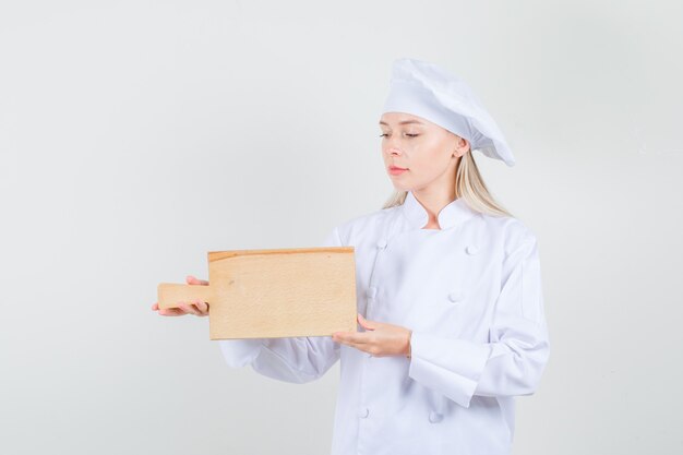 Female chef holding cutting board in white uniform