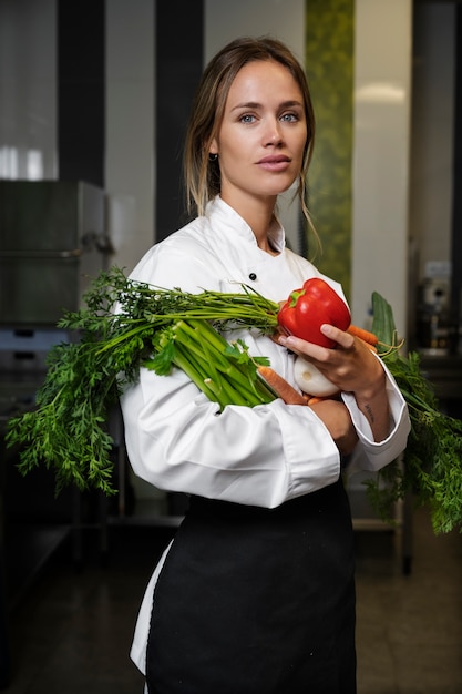 Free photo female chef in the kitchen holding vegetables