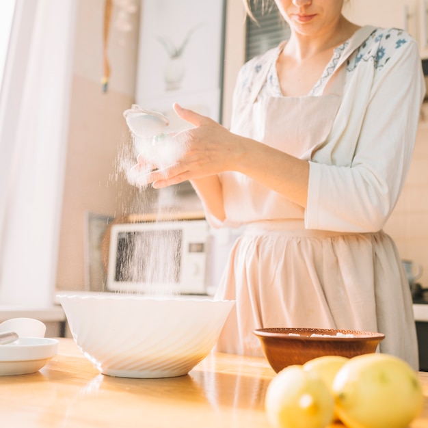 Female chef in a kitchen prepares dough from flour to make pie