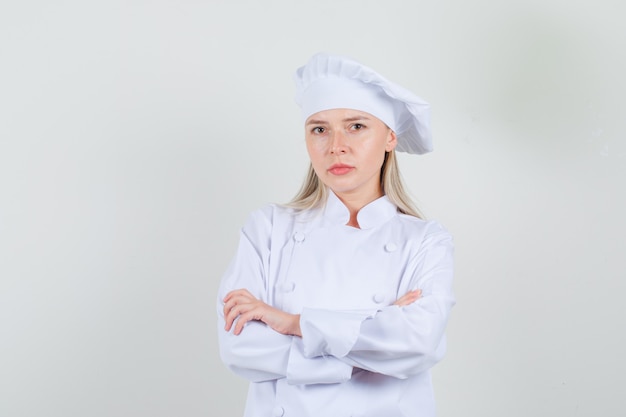 Female chef looking at camera with crossed arms in white uniform and looking serious. front view.