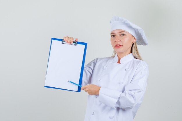 Female chef pointing pencil at clipboard in white uniform 