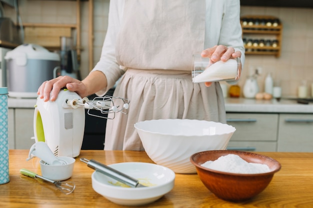 Female chef preparing pie in kitchen with ingredients on table