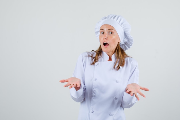 Free photo female chef showing helpless gesture in white uniform and looking confused. front view.