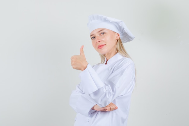 Female chef showing thumb up in white uniform and looking cheerful.