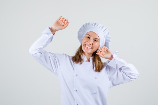 Female chef stretching arms in white uniform and looking cheerful