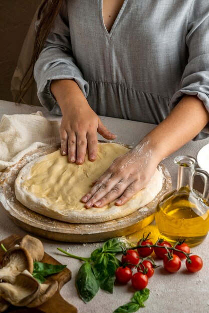 Female chef stretching pizza dough with hands