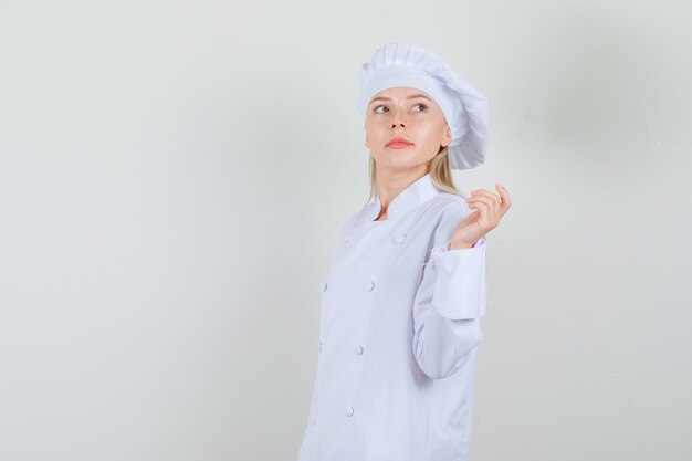 Female chef in white uniform posing while looking aside