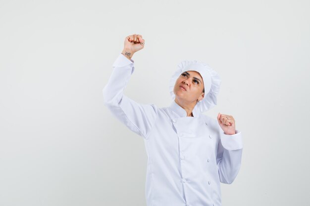 Female chef in white uniform showing winner gesture and looking lucky