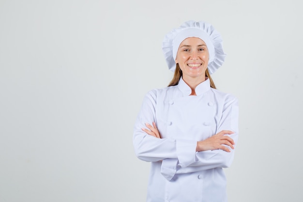 Female chef in white uniform standing with crossed arms and looking cheery