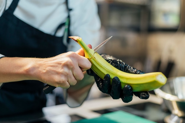 Free photo female chef with glove cutting banana