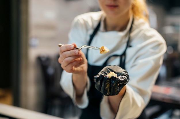 Free Photo female chef with glove testing food if it's cooked