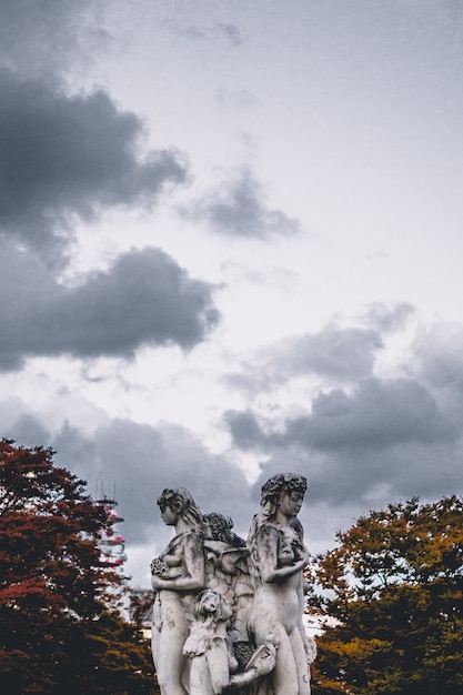 Female concrete statue under white clouds