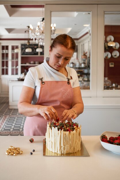 Female confectioner with a strawberry cake in the pastry shop