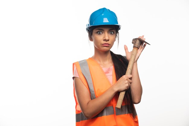 Female construction worker wearing in vest and helmet holding hammer 