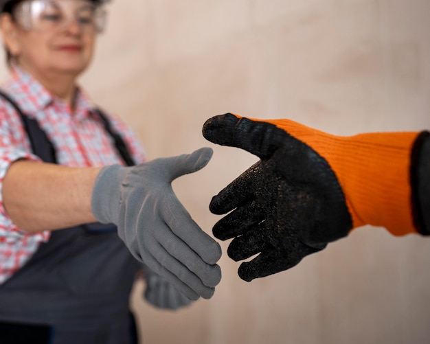 Free photo female construction worker with helmet and gloves giving handshake