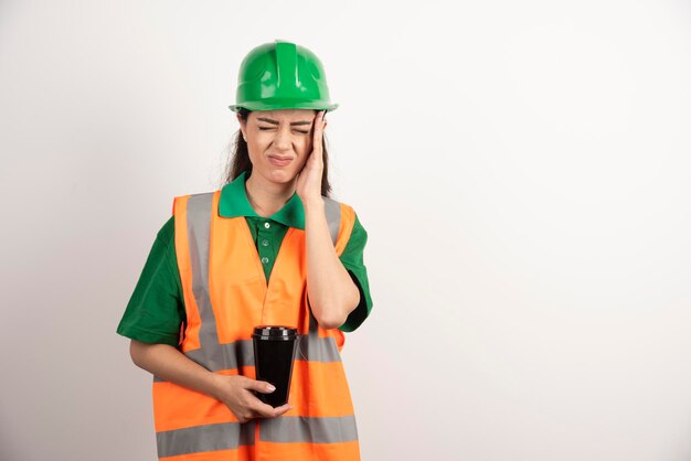 Female constructor with cup touching her head. High quality photo