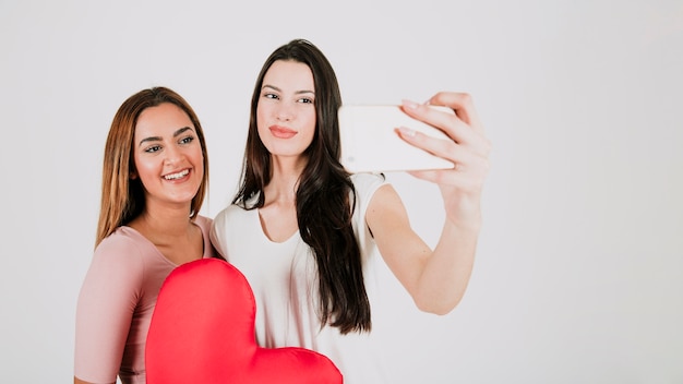 Free Photo female couple taking selfie with heart