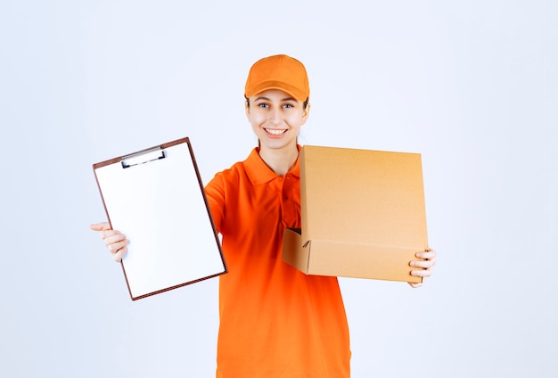 Free photo female courier in orange uniform holding an open cardboard box and asking for a signature