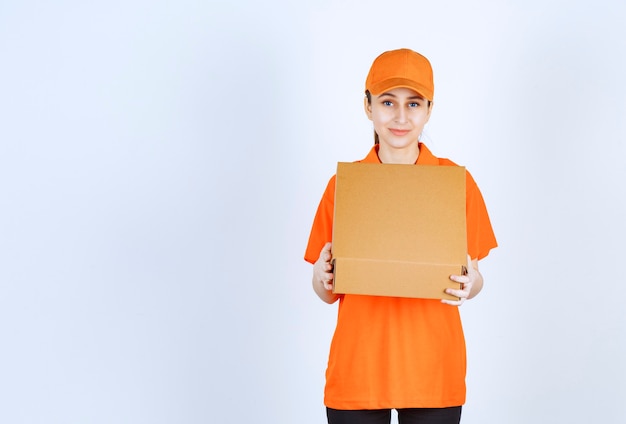 Free photo female courier in orange uniform holding an open cardboard box.