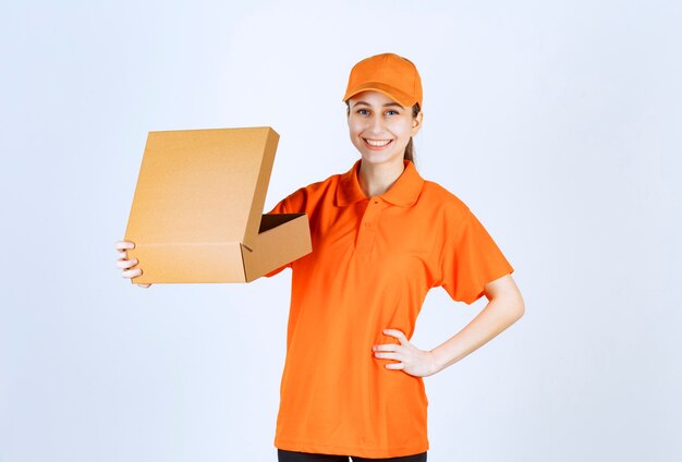 Female courier in orange uniform holding an open cardboard box