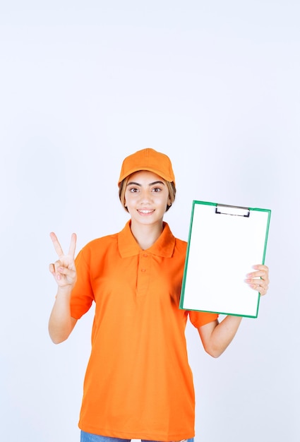 Female courier in orange uniform showing a customer list and showing satisfaction sign