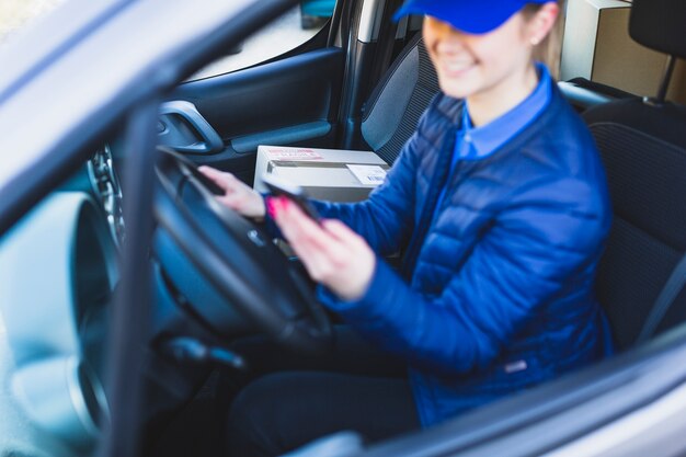 Female courier using phone in car