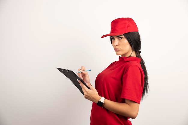 Female courier writing on clipboard with serious expression. High quality photo