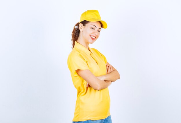 Female courier in yellow uniform crossing arms and giving professional poses. 