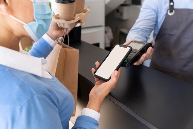 Female customer paying for takeaway food with smartphone