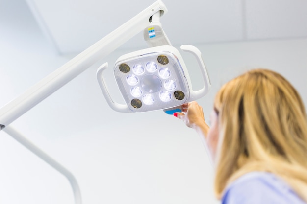 Free photo female dentist adjusting medical lamp in clinic