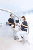 Free photo female dentist scanning patient's teeth with x-ray machine at modern dental clinic