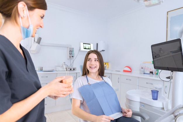 Female dentist showing teeth model to smiling patient