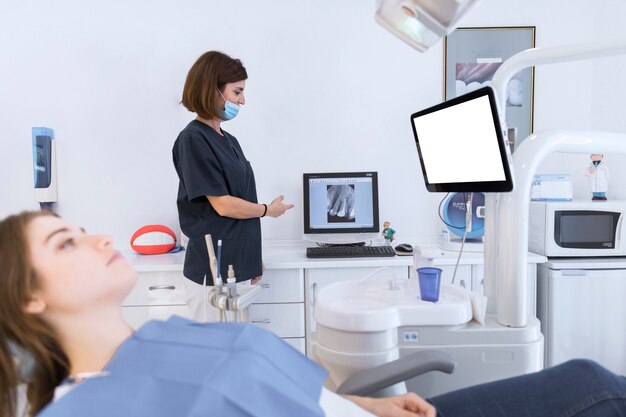 Female dentist showing teeth xray on computer in clinic