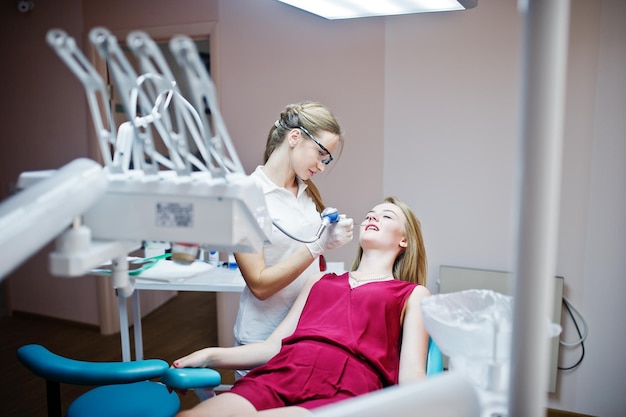 Female dentist in special glasses treating her patient's teeth with dental instruments