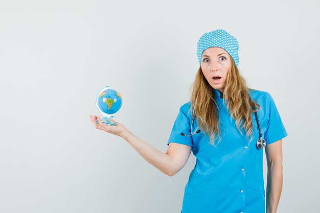 Free Photo female doctor in blue uniform holding world globe and looking anxious 