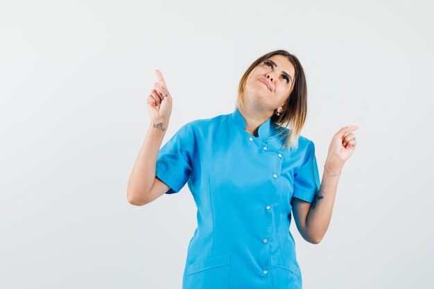 Female doctor in blue uniform looking up and looking hopeful