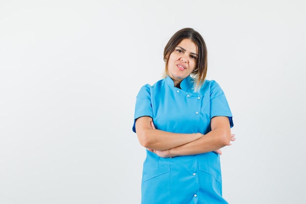 Free photo female doctor in blue uniform standing with crossed arms and looking confident