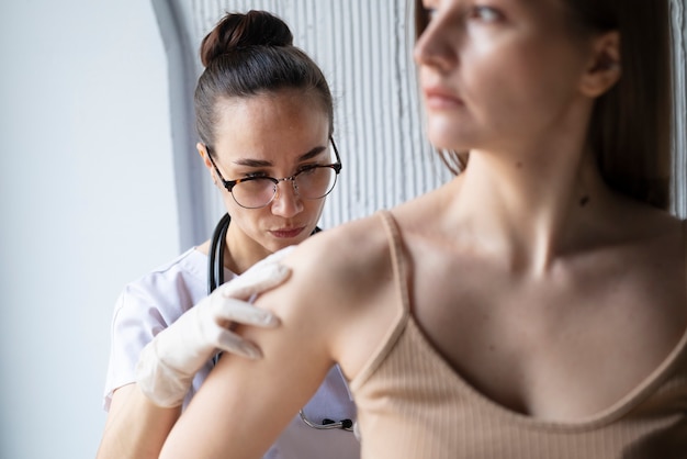 Free photo female doctor diagnosing a melanoma on the body of a female patient