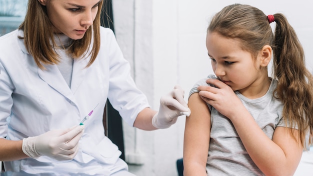 Female doctor giving syringe on sick girl's arm