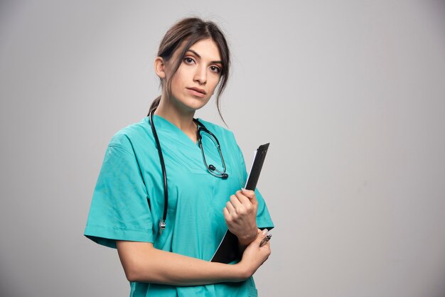 Female doctor holding clipboard on gray