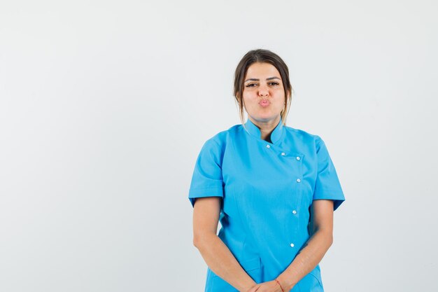 Female doctor keeping lips folded in blue uniform and looking pretty