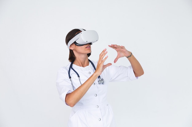 Free photo female doctor in lab coat on white  isolated, wearing virtual reality glasses touch air