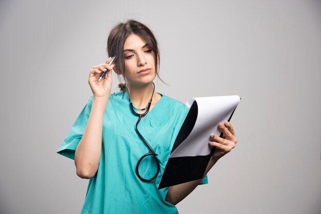 Female doctor looking at notes on clipboard