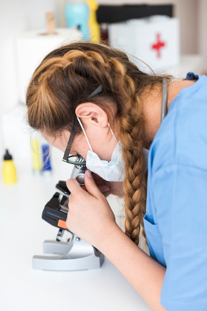 Free photo female doctor looking through a microscope in a laboratory