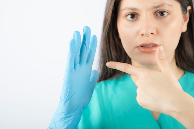 Female doctor in medical gloves showing hands on white. 