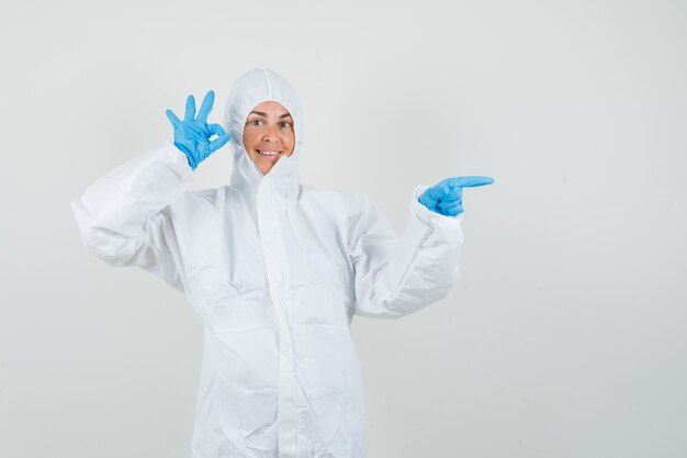 Female doctor in protective suit, gloves pointing to the side