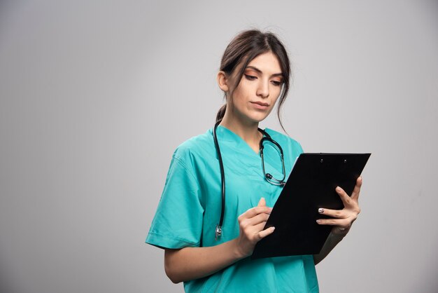 Female doctor reading notes on gray