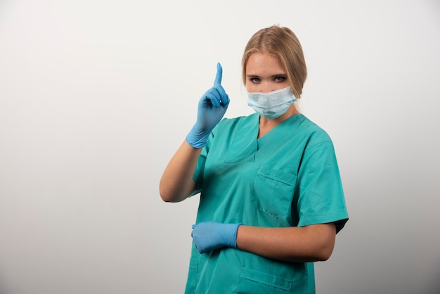 Free photo female doctor showing thumb up and wearing a medical mask.